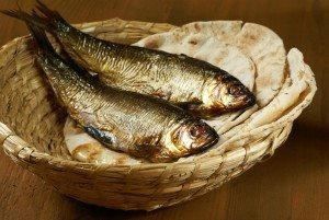 Loaves of bread and two fishes in a basket.